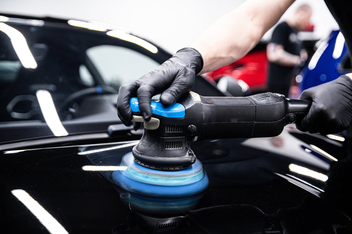 Auto detailer polishing a car in a detailing studio